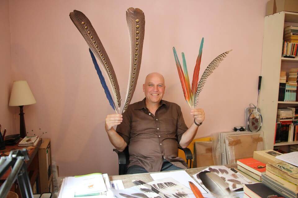 Udo Wellerdieck mit Federn von Argusfasan, Diamantfasan und Ara.